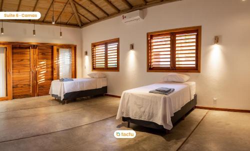 a bedroom with two beds in a room with windows at Casa Mutana Fortim Frente Mar Kiteplace de Luxo in Maceio