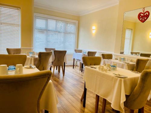 a restaurant with tables and chairs with white table cloth at Cwtch Guesthouse in Llandudno
