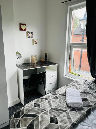 a bedroom with a bed and a desk and a window at Coventry City House - Room 2 in Coventry