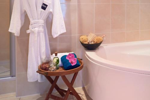 a bathroom with a toilet and a bath tub and a table with towels at Dorint Hotel am Dom Erfurt in Erfurt