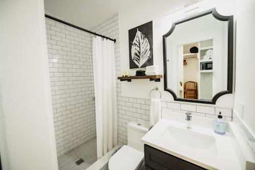 Baño blanco con lavabo y espejo en Marsh Hotel, en Nueva Orleans