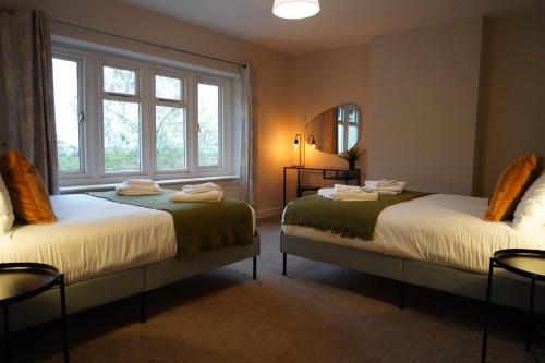 two beds in a room with two windows at The Old Police House- Beautiful Oxfordshire Countryside Retreat- Sleeps 10 in Bicester