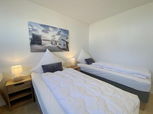- une chambre avec 2 lits et une table de nuit avec 2 lampes dans l'établissement Sternenmeer, à Olpenitz