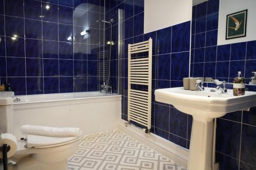 a blue tiled bathroom with a sink and a tub at The Old Police House- Beautiful Oxfordshire Countryside Retreat- Sleeps 10 in Bicester