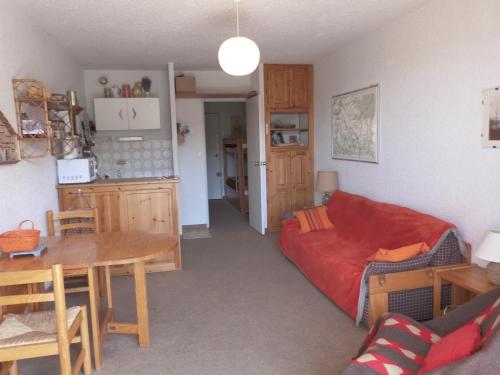 un salon avec un canapé rouge et une table dans l'établissement Studio au cœur du Sauze, à Enchastrayes