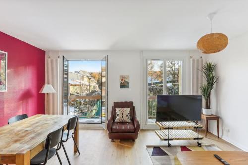 ein Wohnzimmer mit einem Tisch und einem Großbild-TV in der Unterkunft Villa Botanique - Maison avec jardin in Villers-lès-Nancy