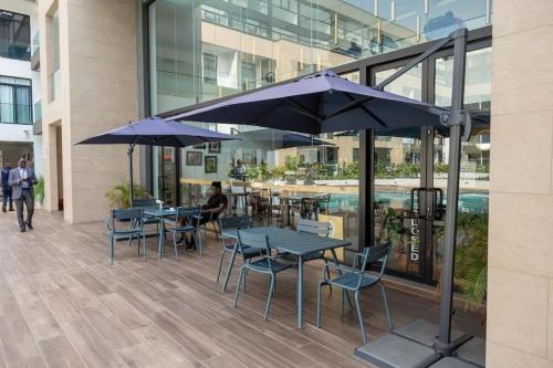 a group of tables and chairs with umbrellas in a building at Cosy 1 Bedroom @Embassy Gardens in Cantonments