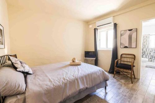 a bedroom with a bed and a chair and a window at Kalkara 4 in Cospicua