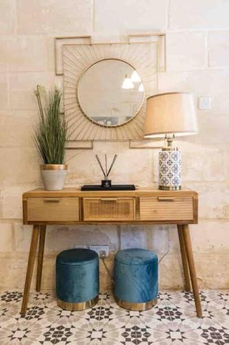 a wooden dressing table with a mirror and a lamp at Kalkara 4 in Cospicua