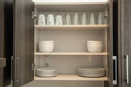 a cupboard with plates and bowls and dishes in it at Cosy 1 Bedroom @Embassy Gardens in Cantonments
