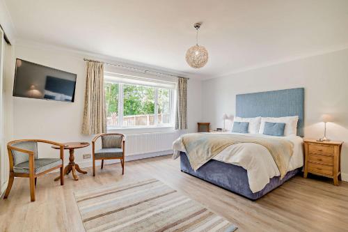 a bedroom with a bed and a desk and a table at Conifers in Lyme Regis