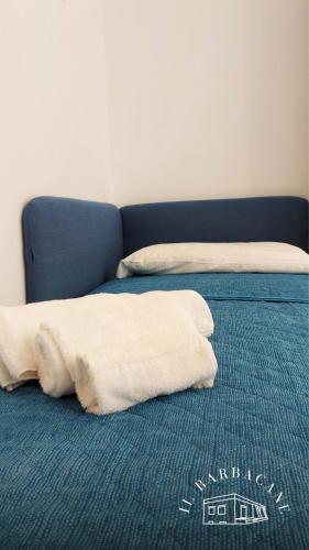 two white pillows on a bed with a blue couch at Il Barbacane in Bacoli