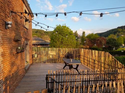 - une table de pique-nique sur une terrasse en bois à côté d'une clôture dans l'établissement Les Chambres de la Fromagerie d'Ambly, à Nassogne