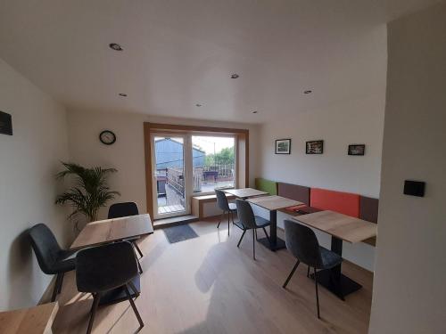 a room with tables and chairs and a window at Les Chambres de la Fromagerie d'Ambly in Nassogne