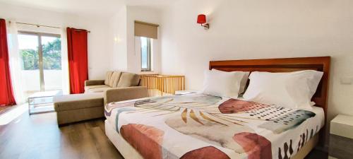ein Schlafzimmer mit einem Bett, einem Sofa und einem Stuhl in der Unterkunft Villa Tenazinha I in Albufeira
