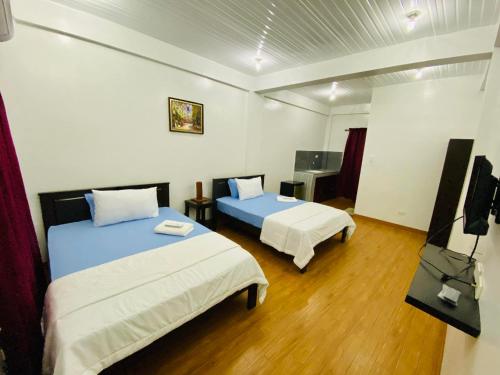 a room with two beds and a television in it at JL Valley Suites in Cauayan City