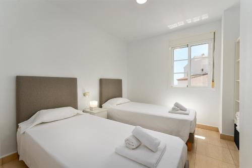two beds in a white room with a window at Duquesa Regent 2435 Wonderful seaviews duplex in Manilva