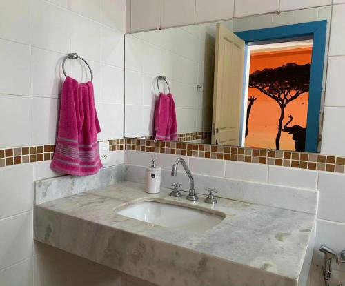 a bathroom with a sink and a mirror and pink towels at Del Mundo Hostel in São João del Rei