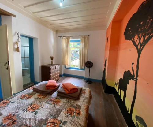 a bedroom with a bed with a tree painted on the wall at Del Mundo Hostel in São João del Rei