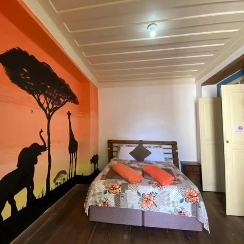 a bedroom with a bed with a tree and giraffe at Del Mundo Hostel in São João del Rei