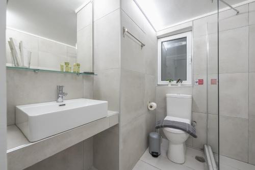 a white bathroom with a sink and a toilet at CONTEMPORARY APARTMENT 200M FROM ACROPOLIS 100Mbps NETFLIX in Athens