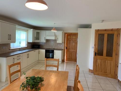 a kitchen with a wooden table and chairs in it at Elm Park Escape - 4 bed self-catering holiday home in Buncrana
