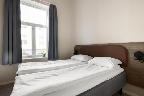 a bed with two white pillows and a window at Maya Apartments - Parkveien in Oslo