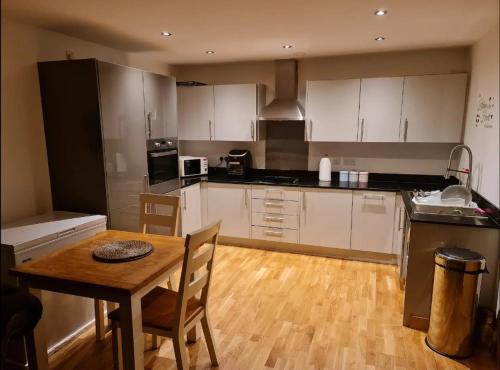 a kitchen with white cabinets and a wooden table at Entire Lovely 2 Bedroom Apartment in Southend-on-Sea