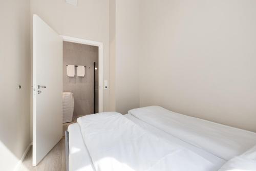 a white bedroom with a white bed and a mirror at Maya Apartments - Parkveien in Oslo