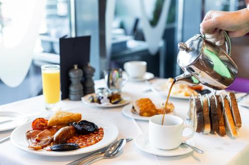 a person pouring coffee into a cup on a table with food at The Royal Yacht in Saint Helier Jersey