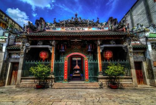 ein asiatisches Gebäude mit einem Tor und Blumen davor in der Unterkunft T Zone Hostel in Ho-Chi-Minh-Stadt