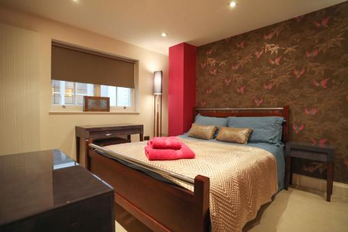a bedroom with a bed with a red pillow on it at The London Nest: 2BR City Haven in London