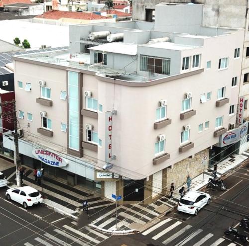 a large white building with cars parked in front of it at Alpha Ville Hotel in Assis