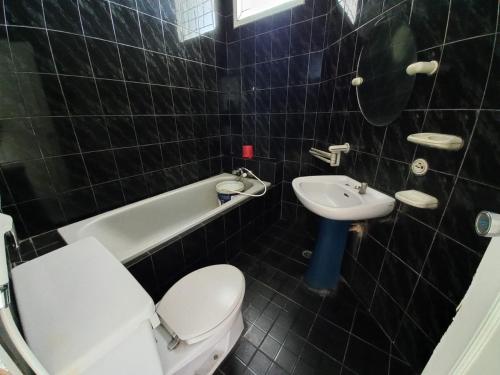een zwart betegelde badkamer met een toilet en een wastafel bij Villa Ciloto Ambarita in Cimacan