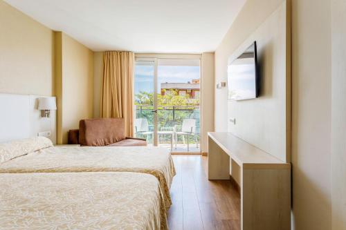 a hotel room with a bed and a desk and a window at Hotel Best Maritim in Cambrils