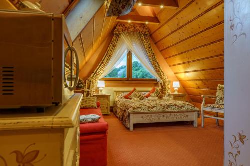 sypialnia w drewnianym domku z łóżkiem i oknem w obiekcie Leśny Dworek Zakopane w Zakopanem