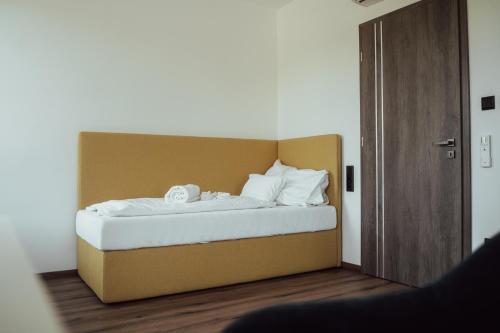 uma cama com lençóis brancos e almofadas num quarto em Fitromax Apartmanház em Ajka