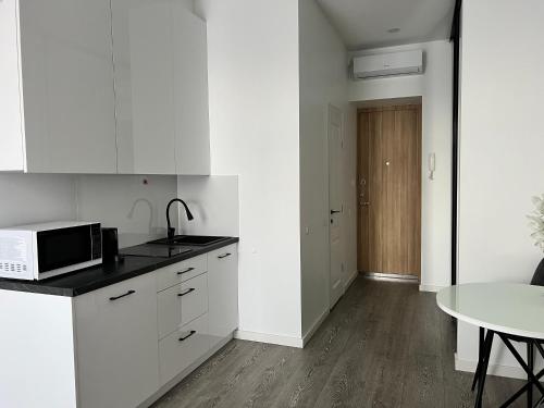 - une cuisine blanche avec une table et un four micro-ondes dans l'établissement Arena apartment, à Kaunas