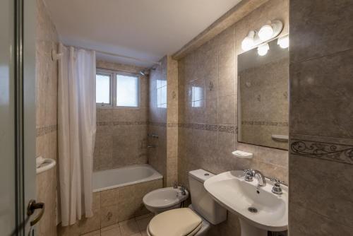een badkamer met een toilet, een wastafel en een bad bij Departamento familiar en Nueva Cordoba by lofty in Cordoba