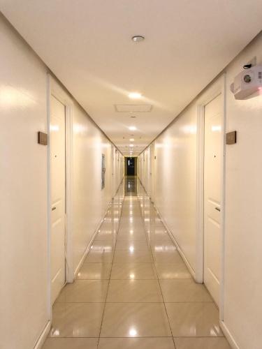 a long hallway with white walls and tile floors at The Crash Pad in Manila