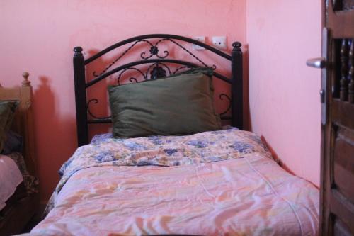 Una cama en una habitación rosa con colcha. en auberge le SIRWA SALAM, en Ouarzazate