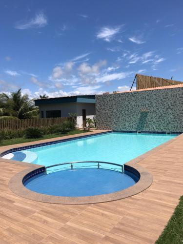 duży basen z drewnianą podłogą i budynek w obiekcie Refugio Caminho da Praia w mieście Anchieta