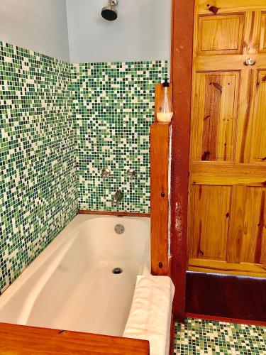 a bath tub in a bathroom with a tiled wall at El Refugio La Brisa del Diablo in Valle Hornito
