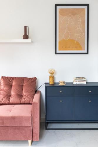 a living room with a pink couch and a dresser at MOVEEN! Wynajem apartamentów we Wrocławiu! 10 minut od centrum in Wrocław