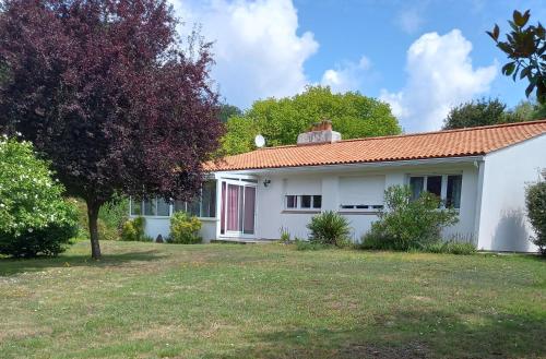 a white house with a red door and a yard at La Gisière, Chambres d'hôtes in Challans
