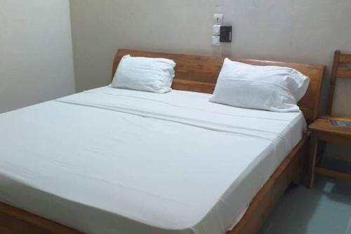 1 cama con sábanas blancas y almohadas en una habitación en Ouidah Lodge, en Ouidah