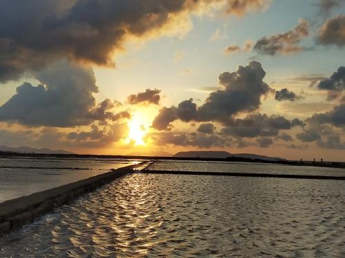 a sunset on the beach with the sun setting at B&B Le Macine 1868 in Paceco