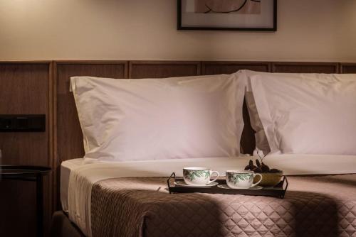 a bed with two cups and a tray on it at Ermioni Luxury Suite Beachfront 1 minute from the beach in Stalida