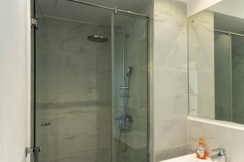 a shower with a glass door in a bathroom at Cosy 2 Bed at Embassy Gardens in Cantonments