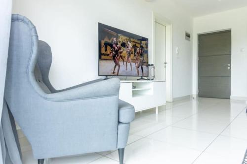 a living room with a blue chair and a tv at Cosy 2 Bed at Embassy Gardens in Cantonments